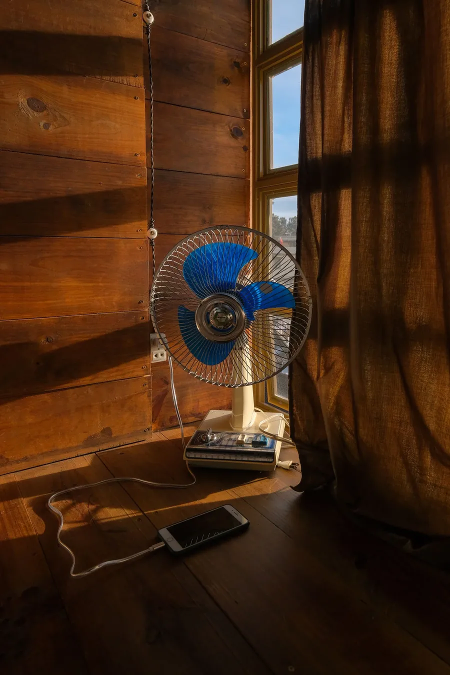 Electric fan by an open window in a room too hot to sleep