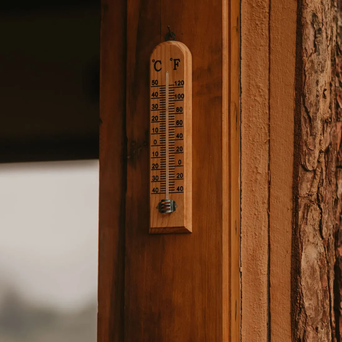Thermometer on a wooden door frame, checking whether a bedroom is too hot for sleep in winter